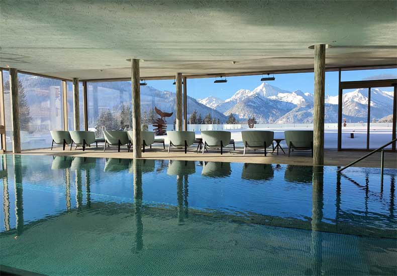 Vanuit het binnenbad van Hotel Bergblick & Spa heb je prachtig uitzicht op de bergen en kun je zo naar buiten zwemmen. © Hotel Bergblick