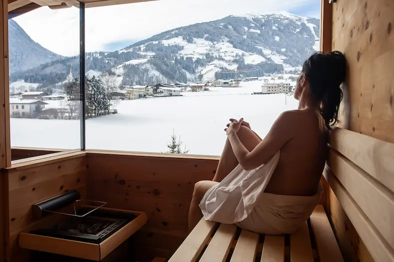 Vanuit de privé-sauna's op de balkons van de Tirol-suites heb je een prachtig uitzicht op de bergketen en de weilanden achter het hotel. De suana's zijn groot genoeg dat 2 personen languit op de banken kunnen liggen. © Hotel Held