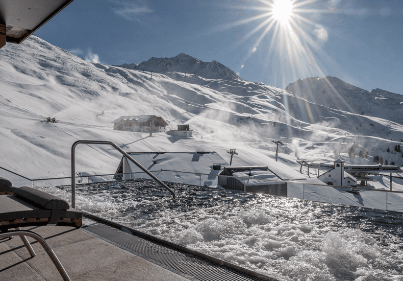 Vanuit de wellness en het bubbelbad buiten kun je de skiërs op de piste voorbij zien komen. © Alexander Maria Lohmann